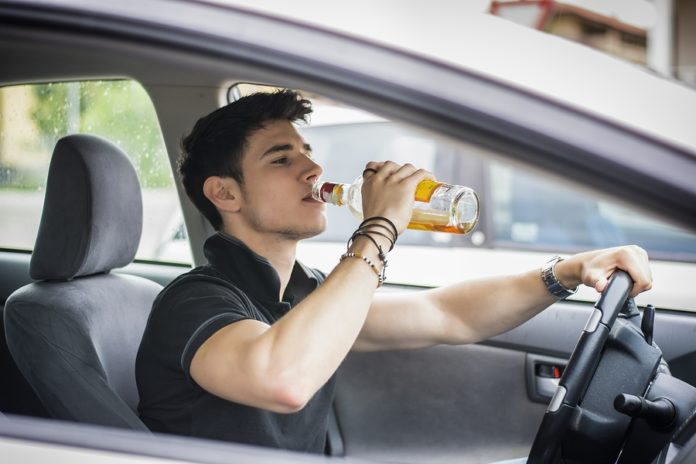 mężczyzna pije alkohol podczas jazdy