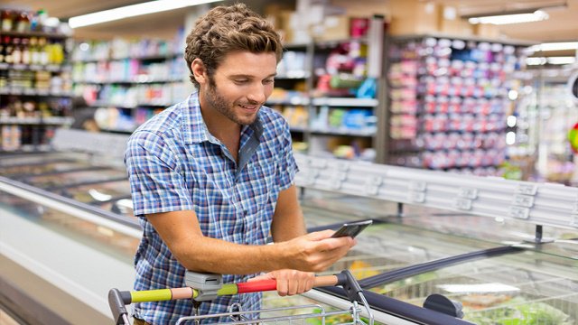 mężczyzna z telefonem w supermarkecie